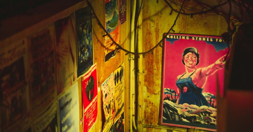 High angle of different placards of musical group on metal walls of weathered construction