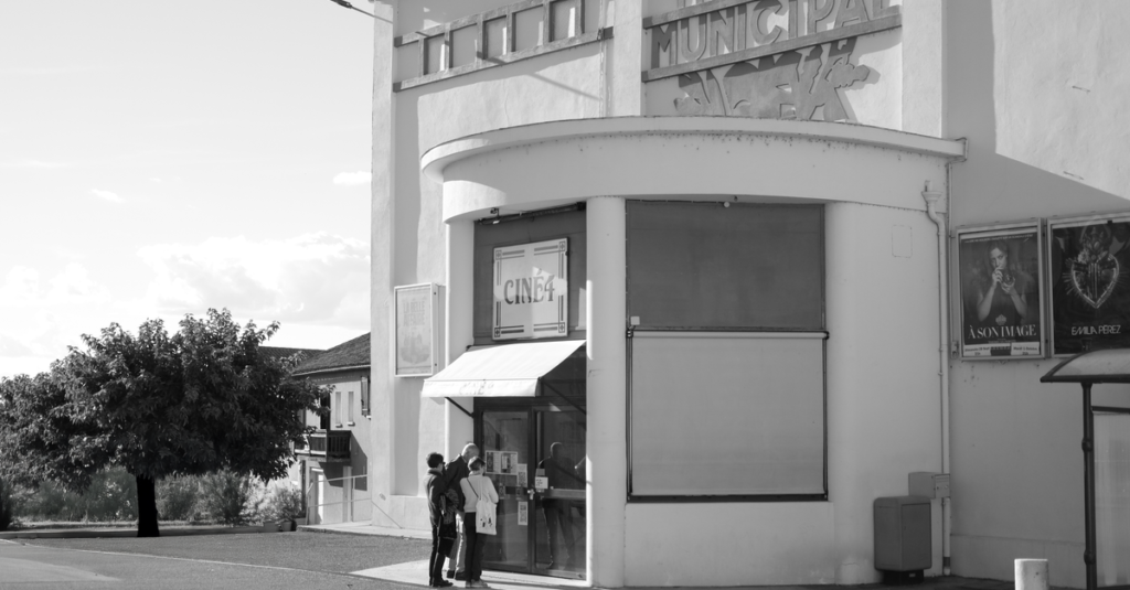 Retro theater entrance with patrons in black and white, evokes a classic cinematic feel.