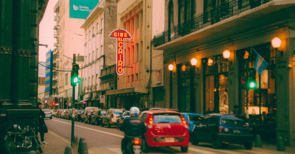 Colorful street scene in Rosario, Argentina, featuring the iconic El Cairo Cinema and urban traffic at dusk.