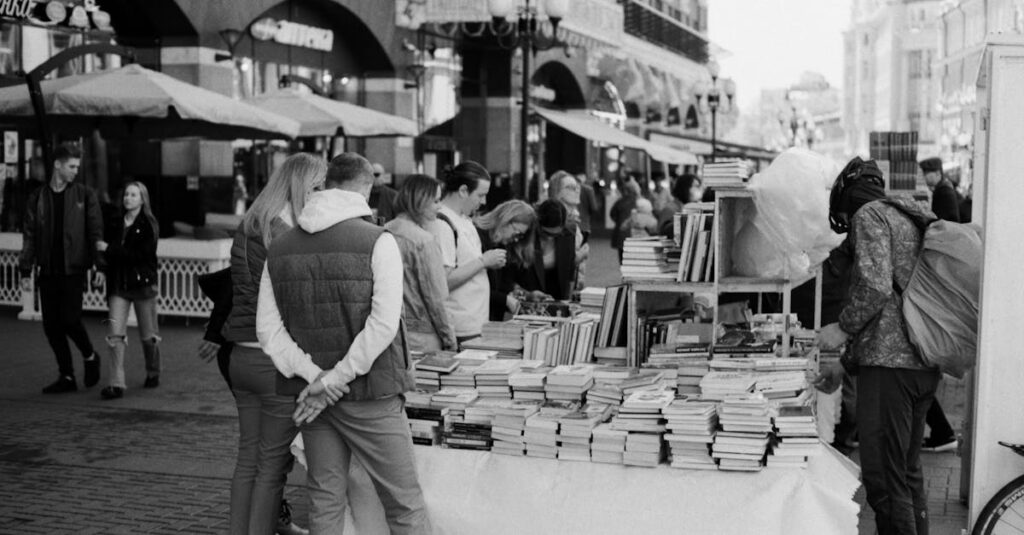 A busy street market with people browsing books at an outdoor stall.