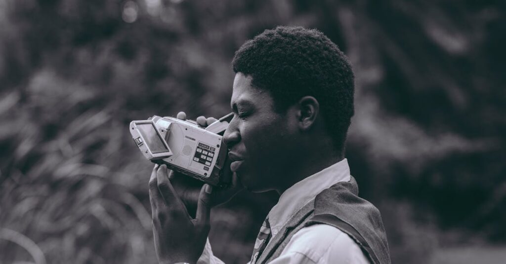 Portrait of a man with a vintage video camera in a natural setting, showcasing style and nostalgia.