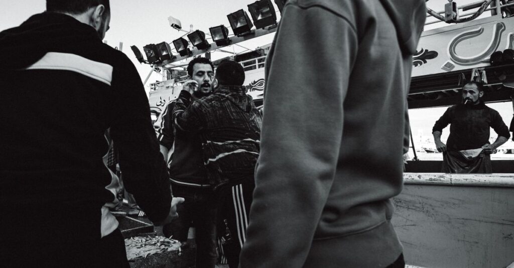 Candid black and white street photo depicting a group of people interacting energetically.