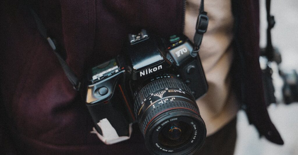 Close-up of a photographer holding a classic Nikon film camera, capturing street life outdoors.
