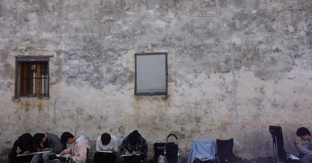 People sketching by an urban wall, capturing street art in a serene setting.
