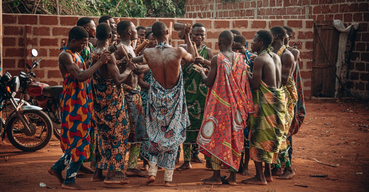 A vibrant cultural ceremony in Benin featuring a group in traditional clothing engaging in a ritual dance.
