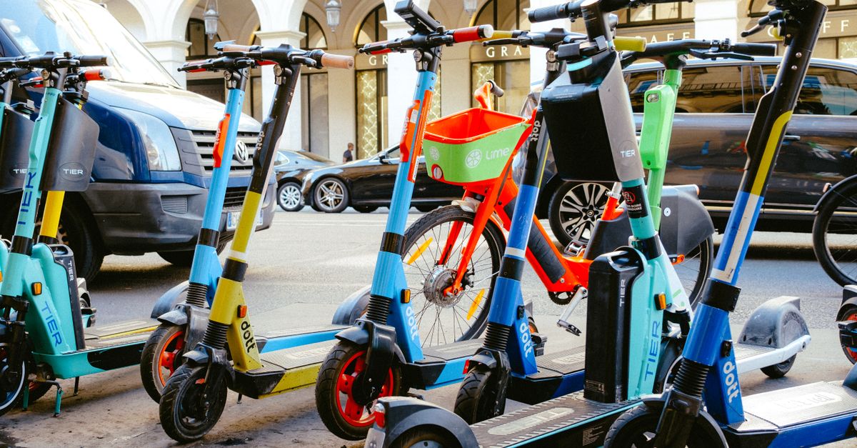 A vibrant collection of electric scooters and bicycles parked on a bustling city street.