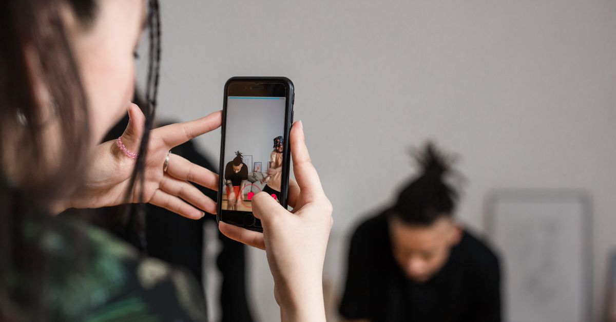 Close-up of a person recording a video with a smartphone indoors, focusing on creative content creation.