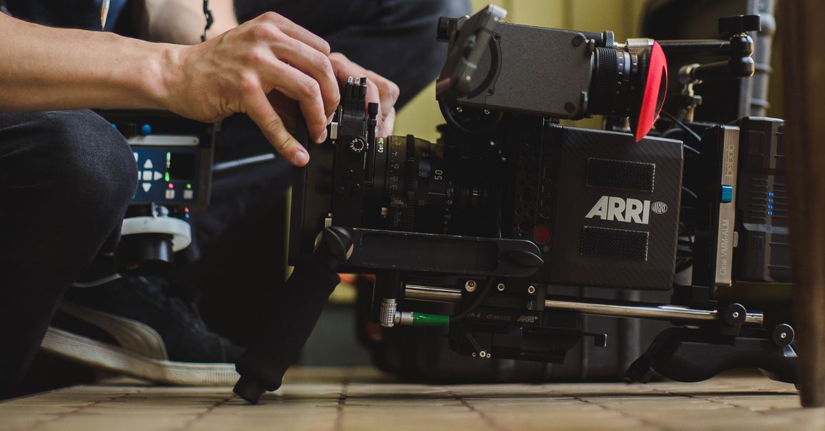 Close-up of hands adjusting a professional ARRI film camera on a production set, showcasing filmmaking equipment.