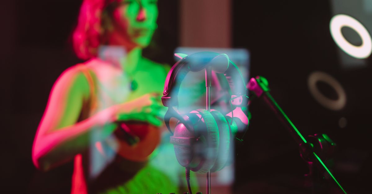 Musician recording in a vibrant studio with headphones and audio equipment glowing in neon lights.