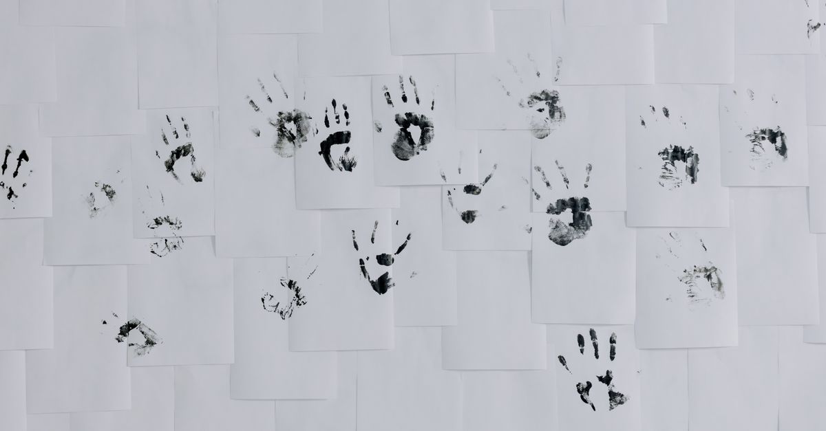 Black handprints artistically arranged on a white wall of papers, minimalist and creative still life.