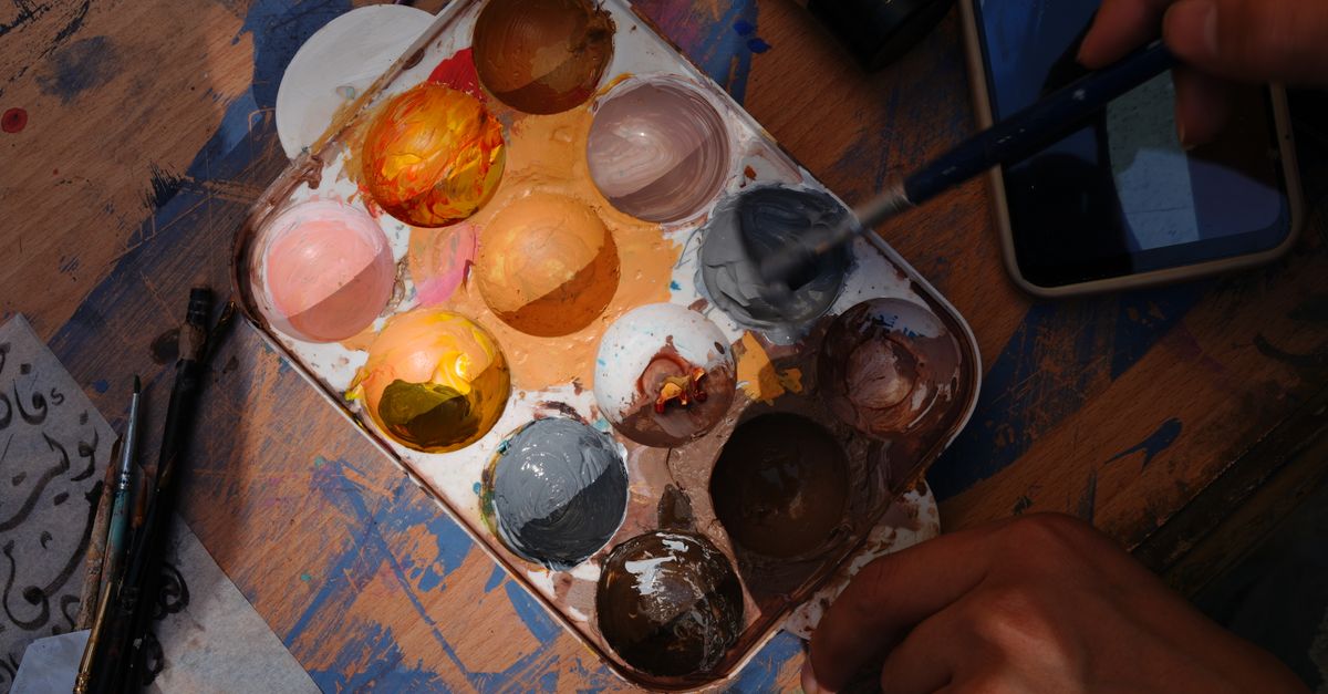 Vibrant artist palette with brushes in a Damascus studio setting, showcasing creativity and art tools.