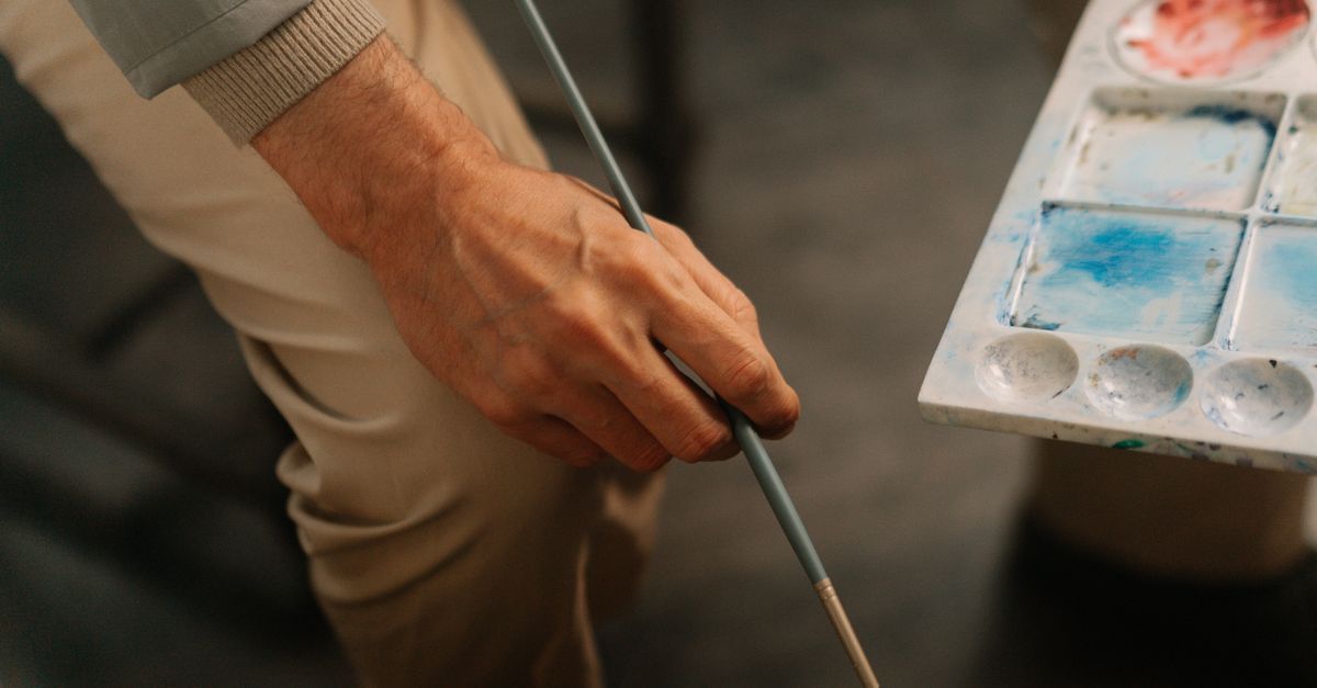 Close-up of an artist holding a paintbrush and palette, perfect for creative themes.