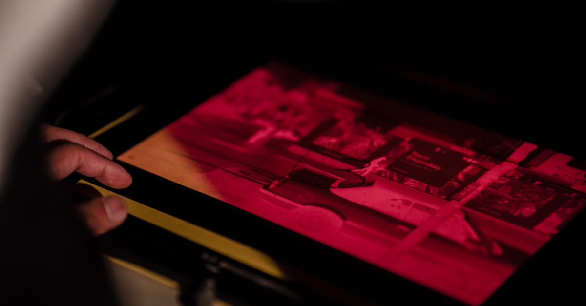 Hand working with photographic film under red light in a darkroom environment.