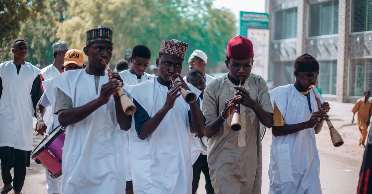 A vibrant street parade featuring traditional African musicians playing instruments and marching.
