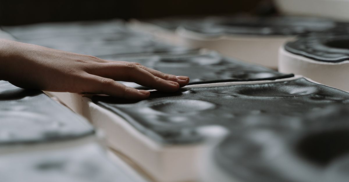 Close-up of a hand touching textured craft material, emphasizing artistic details and tactile qualities.