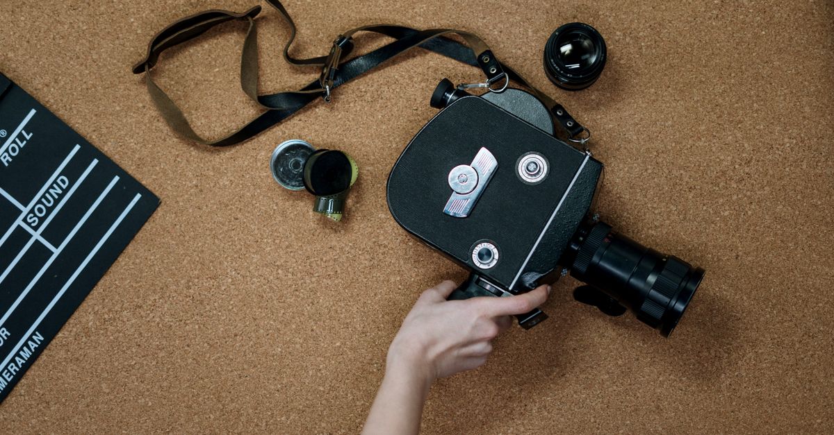 A vintage analog camera and clapboard on a cork surface, representing classic cinematography.