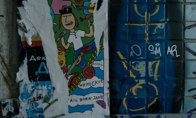 Vibrant street art poster on a graffiti-covered urban wall, depicting musical themes and abstract designs.