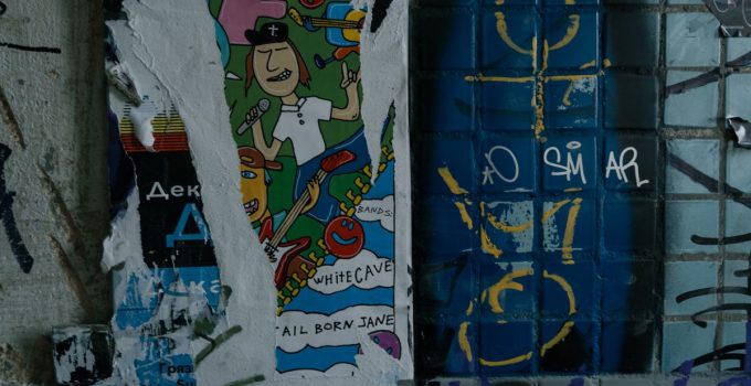 Vibrant street art poster on a graffiti-covered urban wall, depicting musical themes and abstract designs.