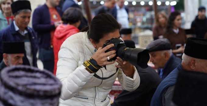 A female photographer captures cultural moments at an outdoor event with her camera.