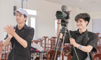 Two young filmmakers working with a camera in a bright studio.