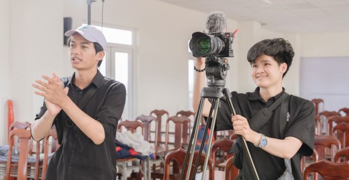 Two young filmmakers working with a camera in a bright studio.
