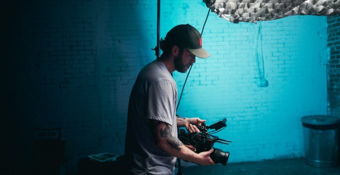 Cinematographer fine-tuning camera settings on a film set with professional lighting.