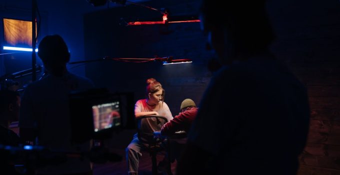 Indoors film set illuminated by neon lights, showcasing a camera crew in action.