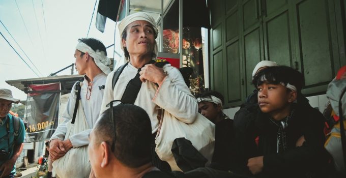 Group of adults and teenagers in traditional attire, engaged in street scene with vibrant atmosphere.