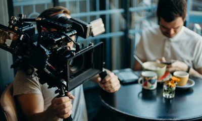 Cameraman filming a scene in a cozy cafe setting, capturing the cinematic atmosphere.