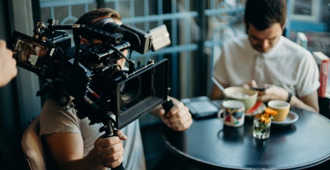 Cameraman filming a scene in a cozy cafe setting, capturing the cinematic atmosphere.