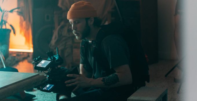 Professional cinematographer working indoors with camera gear, showcasing concentration and creativity during filming.
