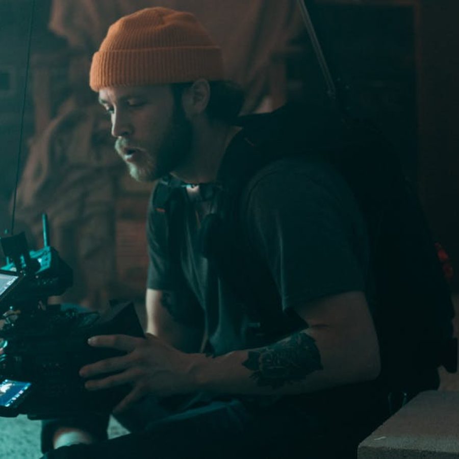 Professional cinematographer working indoors with camera gear, showcasing concentration and creativity during filming.