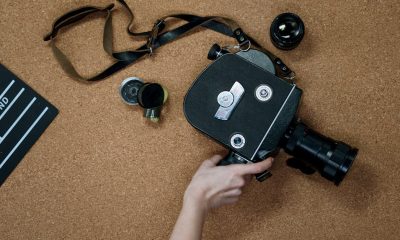 A vintage analog camera and clapboard on a cork surface, representing classic cinematography.