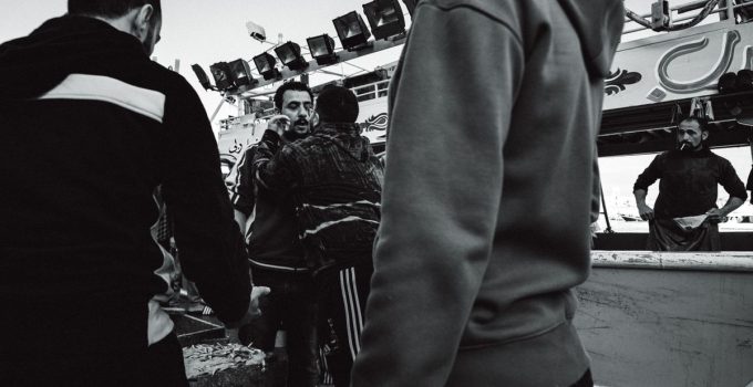 Candid black and white street photo depicting a group of people interacting energetically.