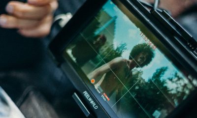 Close-up of a cinematic display showing a filmmaker at work capturing a scene outdoors.