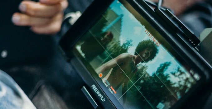 Close-up of a cinematic display showing a filmmaker at work capturing a scene outdoors.
