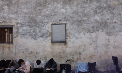 People sketching by an urban wall, capturing street art in a serene setting.