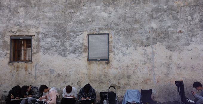 People sketching by an urban wall, capturing street art in a serene setting.