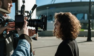 Professional filmmakers capturing a scene outdoors near a stadium, featuring equipment and creative process.
