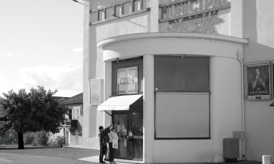 Retro theater entrance with patrons in black and white, evokes a classic cinematic feel.