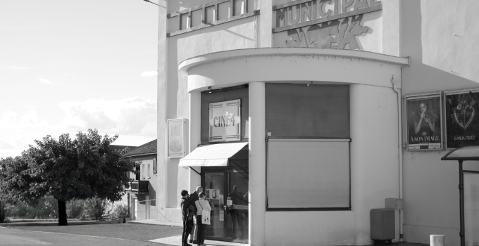 Retro theater entrance with patrons in black and white, evokes a classic cinematic feel.